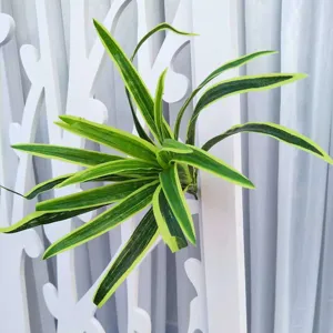 Détail de plante verte artificielle avec des feuilles panachées pour la décoration murale.