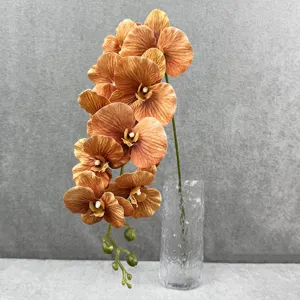 Gedetailleerde close-up van kunstmatige oranje phalaenopsis orchidee bloementak in glazen vaas.