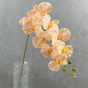 Gedetailleerd overzicht van kunstmatige phalaenopsis orchidee tak in glazen vaas.