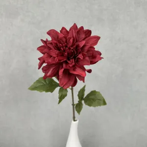 Single artificial dahlia flower with green leaves in white vase for home wedding decor