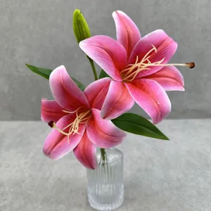 Gros plan d'un arrangement de lys artificiels roses à deux têtes et feuilles dans vase.
