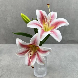 Gros plan de détail d'un arrangement floral de lys 3D artificiel avec deux fleurs, un bourgeon.