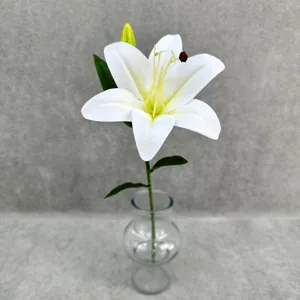 Close-up detail view of artificial white lily flower with green leaves for home decor.