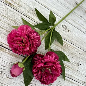 Close-up detail of artificial peony flower stem with three heads and green leaves for home decor.