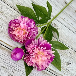 Close-up detail of artificial peony branch featuring vibrant pink and purple blooms with green leaves.