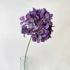 Detailed close-up of a single purple artificial hydrangea flower in a clear vase for decor.