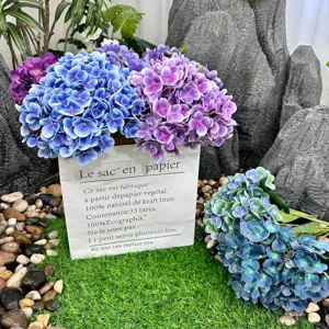Detailed shot of artificial hydrangea flowers in paper bag with natural stone backdrop.