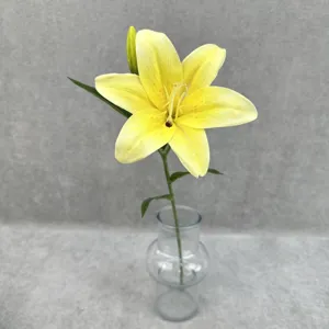 Detailed view of a single stem artificial yellow lily flower in a clear glass vase.