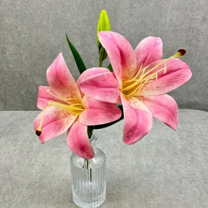 Détail d'arrangement de fleurs de lys rose artificiel avec vase en verre transparent.