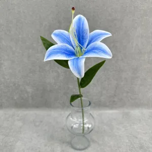 Close-up detail of artificial blue gradient lily flower stem in clear glass vase, home decor
