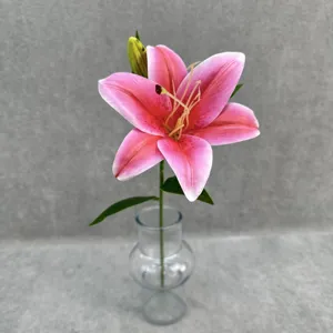Detail closeup of a single pink artificial lily flower in a clear glass vase for decor.