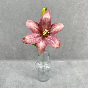 Close-up detail of a single artificial pink lily flower in a clear glass vase for decor.