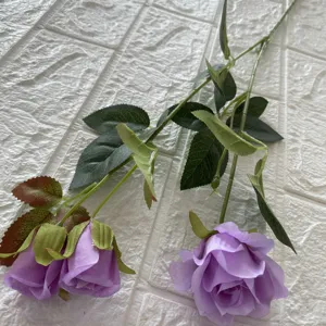 Primo piano di rose artificiali viola con foglie verdi per la decorazione della casa.