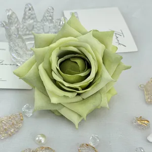 Green artificial rose flower head detail close up for wedding decor DIY craft box.