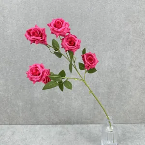Gros plan sur une tige de rose artificielle à 6 têtes avec des feuilles vertes pour la décoration.