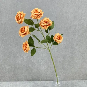Vue détaillée de 6 roses artificielles orange avec feuilles vertes dans un vase pour décor.