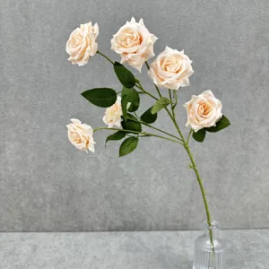 Détail de gros plan époustouflant de roses artificielles champagne avec des feuilles vertes.
