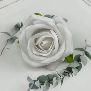 White velvet artificial rose flower head with eucalyptus leaves detail for wedding decor.