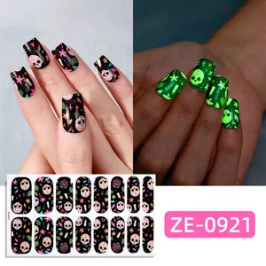 Close-up detail of Halloween glow-in-the-dark skull nail wraps showing vibrant night effect.