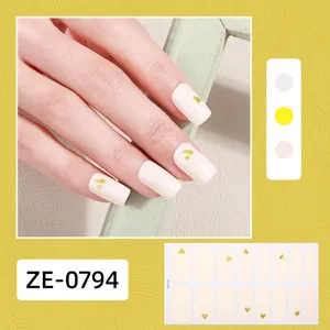 Close-up detail of cream white nail wrap stickers featuring elegant gold heart patterns.