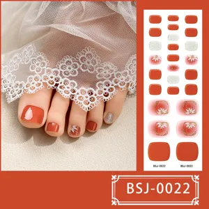 Semi-verharde gel teennagelwraps met oranje glitter en witte bloemenkunst voor pedicure.