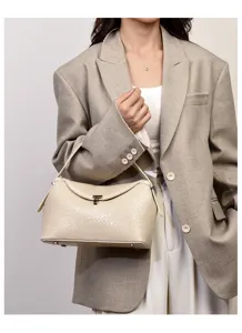 Detailopname van een stijlvolle beige geweven lederen schoudertas met metalen sluiting.