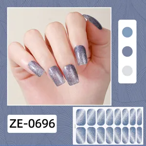 Detailaufnahme von glitzernden Katzenauge Nagelwraps mit blauen Klebestickern für die Maniküre.