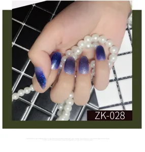 Dettaglio in primo piano di unghie finte glitterate sfumate blu viola con effetto brillante.