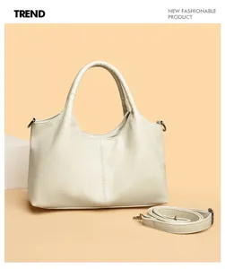 Vista dettagliata di elegante borsa a mano da donna in pelle beige con tracolla e accessori.