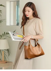 Dettaglio della borsa a tracolla in pelle marrone con interno capiente e stile versatile.