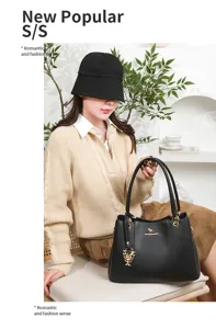 Detail view of black lychee pattern leather shoulder handbag with gold hardware and flower pendant.