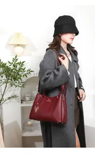 Stylish wine red litchi pattern leather shoulder handbag with elegant golden metal flower pendant.