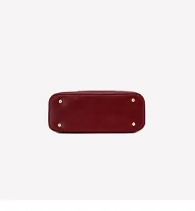 Detail view of burgundy litchi grain women handbag bottom with four gold protective metal feet.