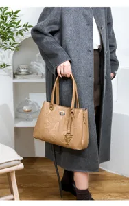 Detailed view of stylish camel embossed letter handbag with elegant metal pendant for women.