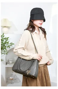Detail view of grey embossed leather handbag featuring metal flower pendant and chic design.