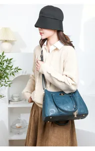 Stylish dark blue leather tote bag with embossed logo letters and metal flower pendant.