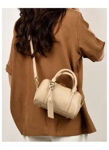 Detailed view of the beige leather Boston shoulder bag showing cross-body wear and metal hardware.