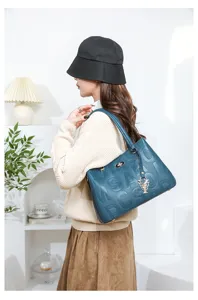 Stylish dark blue leather tote bag with debossed letters and metal flower pendant for women.