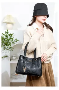 Black embossed letter top-handle handbag with metal flower pendant, stylish women commuting bag.