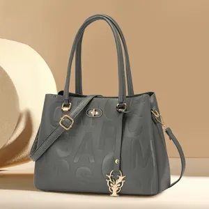 Fashionable grey women handbag with debossed letters and metallic charm for daily commute.