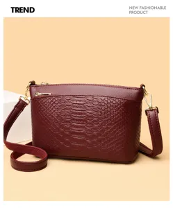 Burgundy alligator pattern crossbody bag detail, premium leather texture with gold hardware.