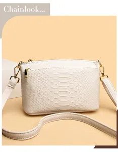 Detail shot of an elegant cream white crocodile pattern crossbody bag with gold tone hardware.