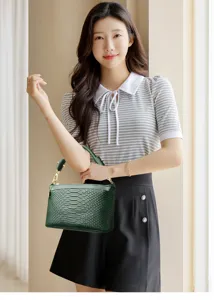 Detail view of the elegant dark green crocodile textured handbag, stylish top handle design for women.