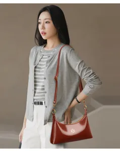 Vue détaillée d'un sac porté épaule en cuir verni brillant avec finitions métalliques.