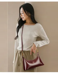 Vue détaillée d'un sac à bandoulière croissant en cuir verni bordeaux avec détails.