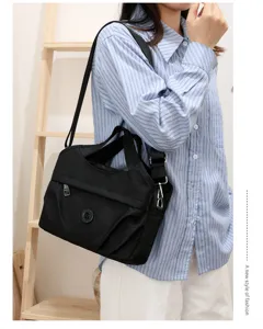 Detailansicht der schwarzen, gefalteten Nylon-Umhängetasche mit mehreren Taschen.