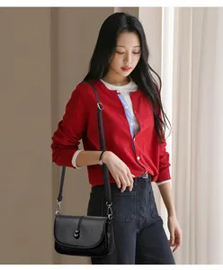 Primo piano della borsa a tracolla in pelle nera indossata dalla modella, stile unico.