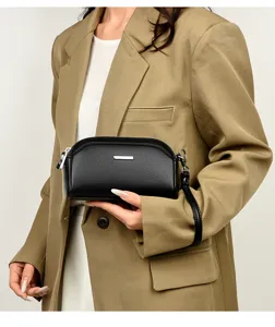 Close-up of black textured leather women clutch bag with silver metal bar and wrist strap detail.