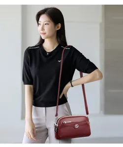 Detailed view of the stylish burgundy leather crossbody phone bag with double compartments and hardware.
