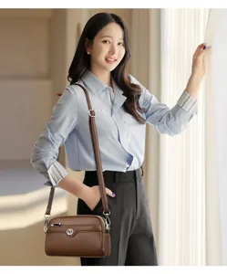 Detail shot of a stylish brown leather crossbody phone bag, elegant double-layer design.